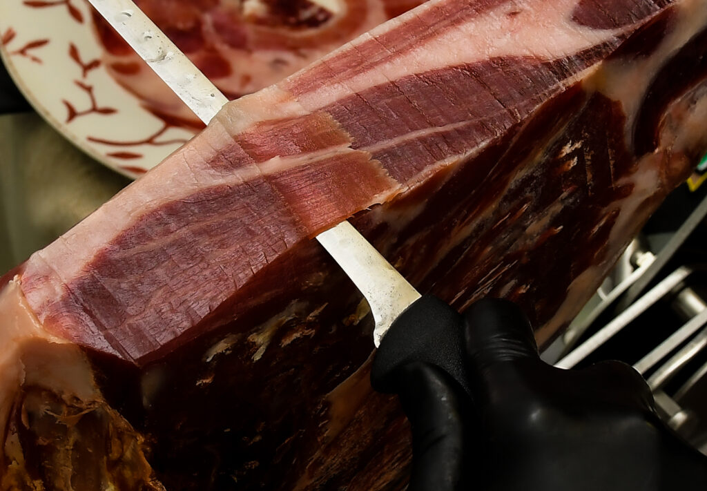 Corte a cuchillo de jamón ibérico vitola y brida negra denominación de origen Dehesa de Extremadura de Industrias Cárnicas El Bellotero.